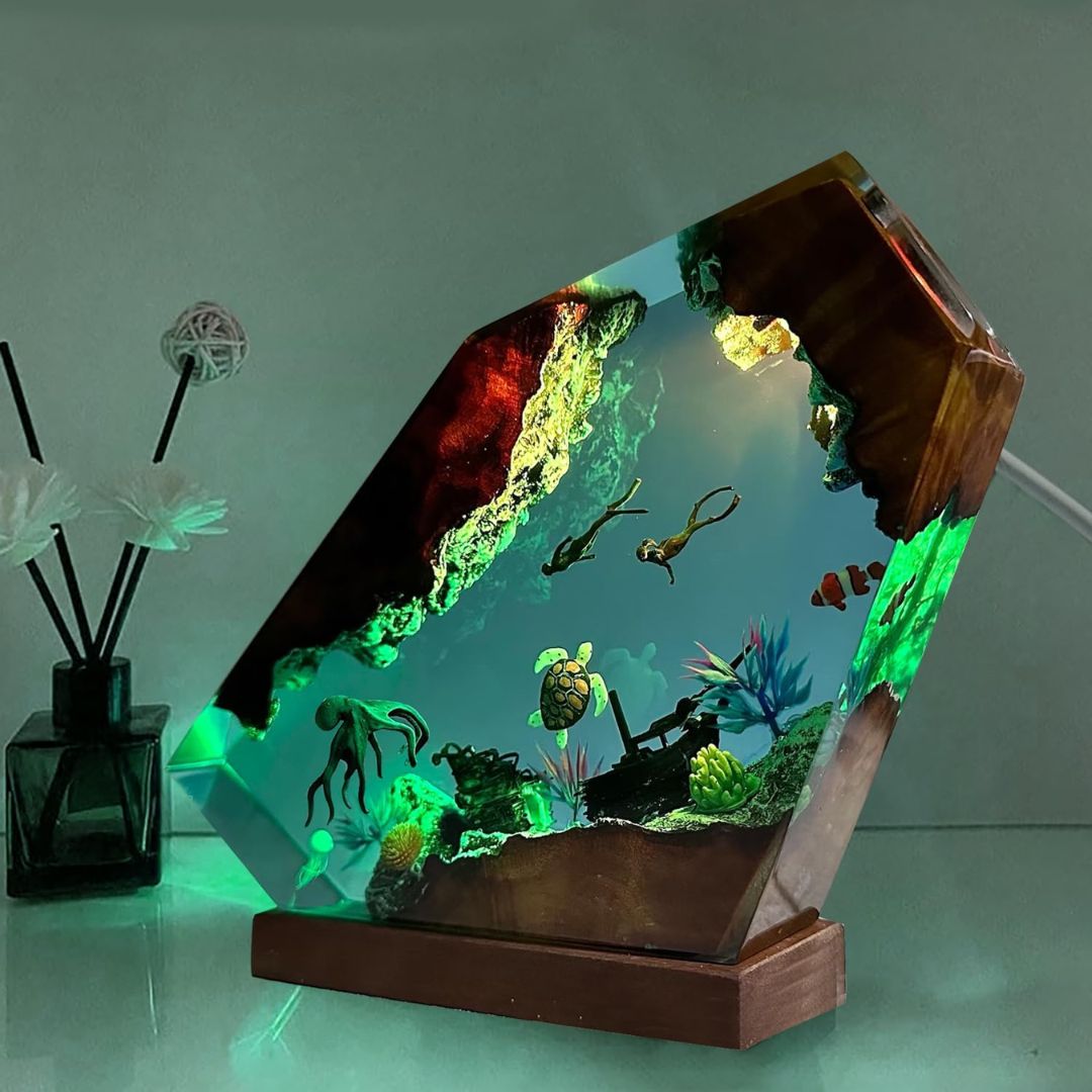 Decorative aquarium with underwater scene inside a wooden frame on a reflective surface.
