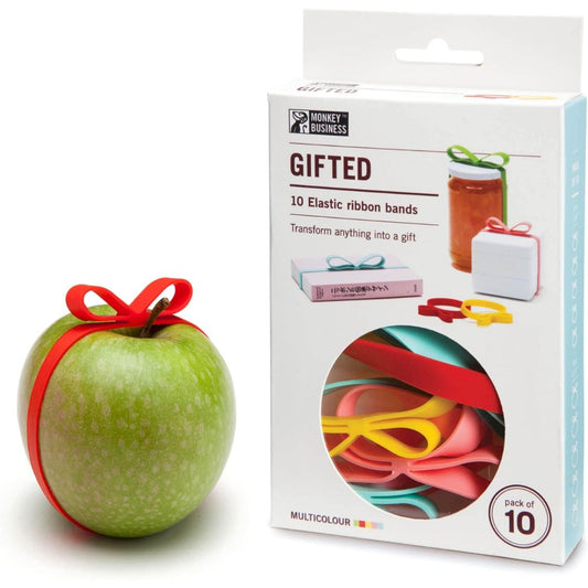 A package of 10 elastic ribbon bands shown next to a green apple wrapped in a red ribbon, on a clean white background. The box is labeled 'GIFTED' by 'Monkey Business' and shows the ribbons in a circular window.