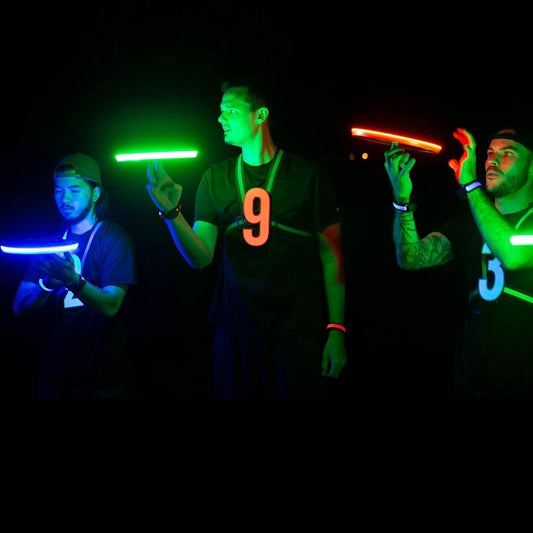 Four people holding glowing flying disks in a dark setting