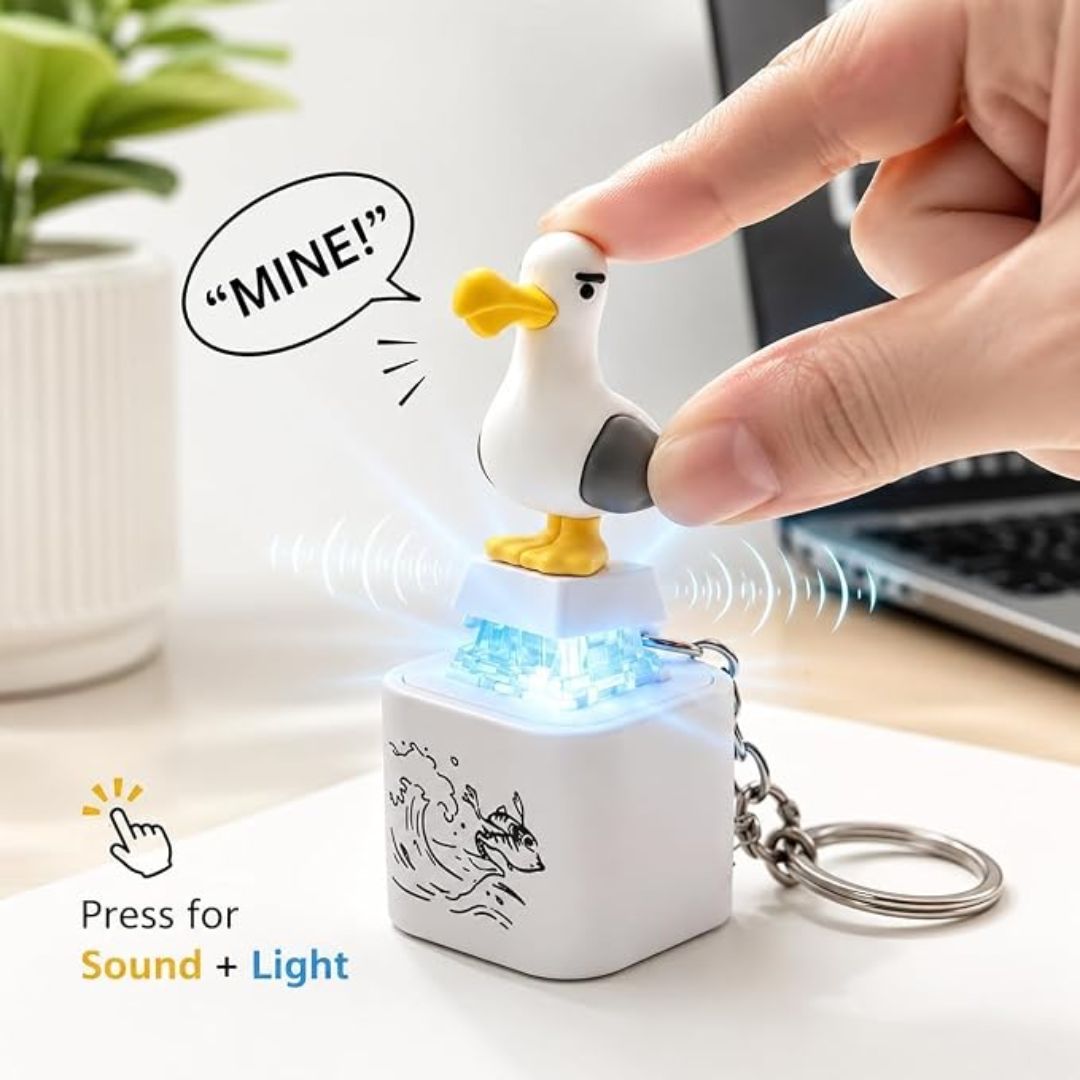 Seagull keychain with sound and light feature being pressed by a hand on a desk.
