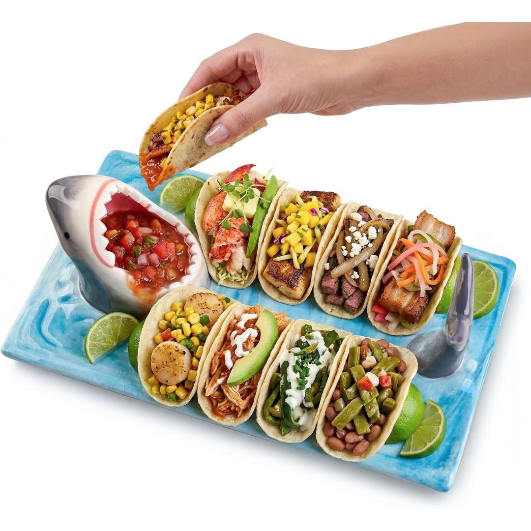 Shark serving platter holding assorted tacos with salsa in the shark mouth bowl and lime wedges