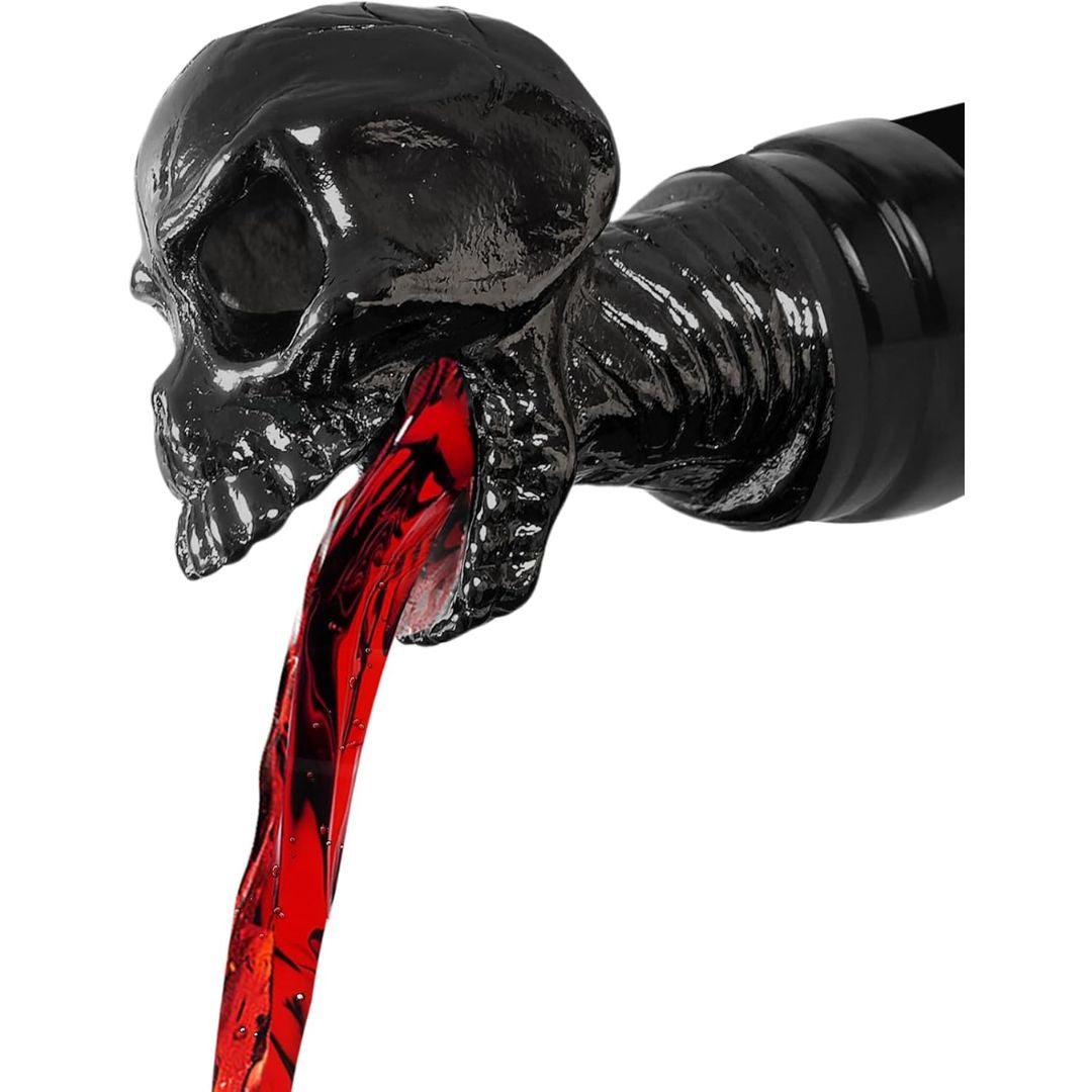 Black skull-shaped wine bottle aerator with red wine spilling out of its mouth on a white background
