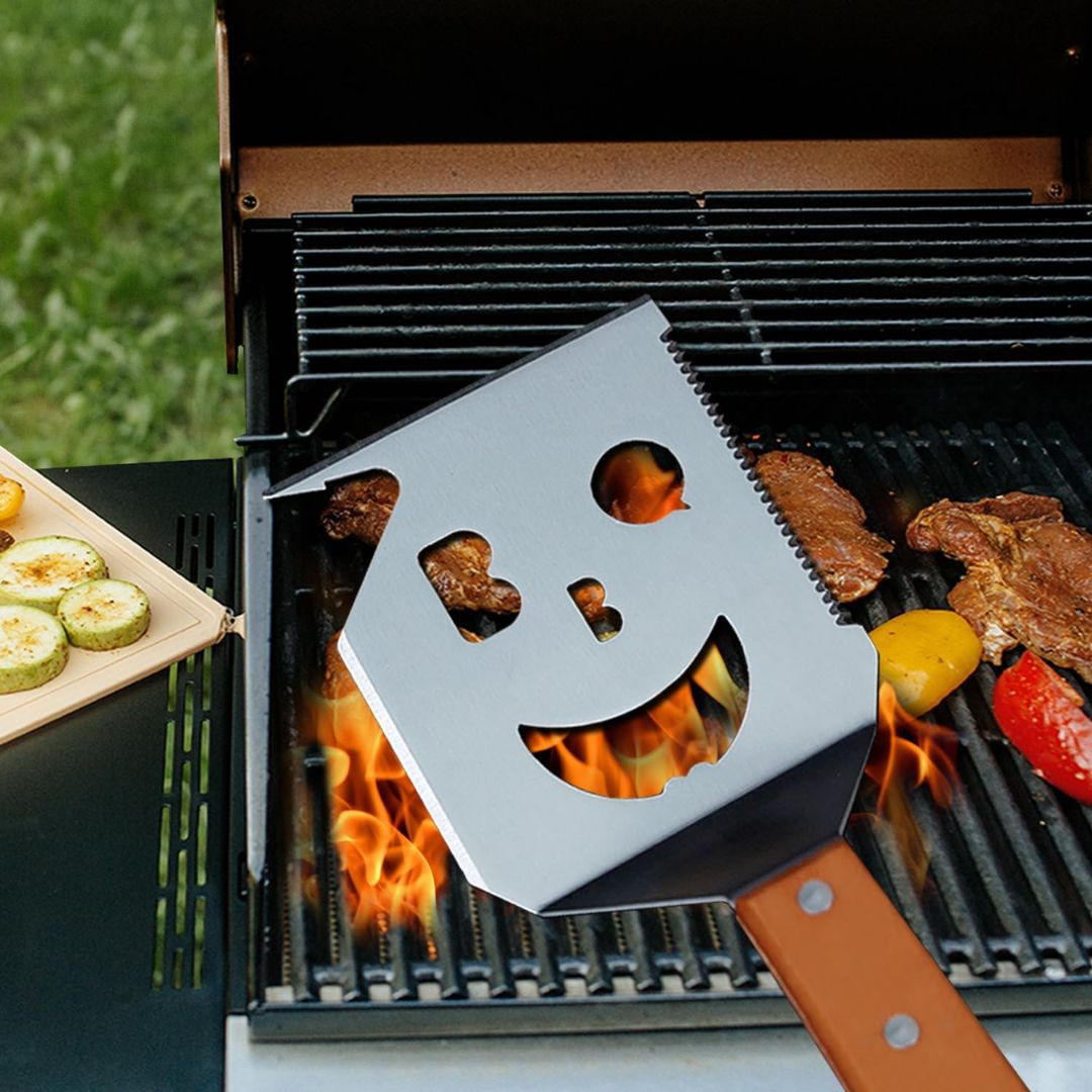 Grill tool with smiley face design in front of a barbecue