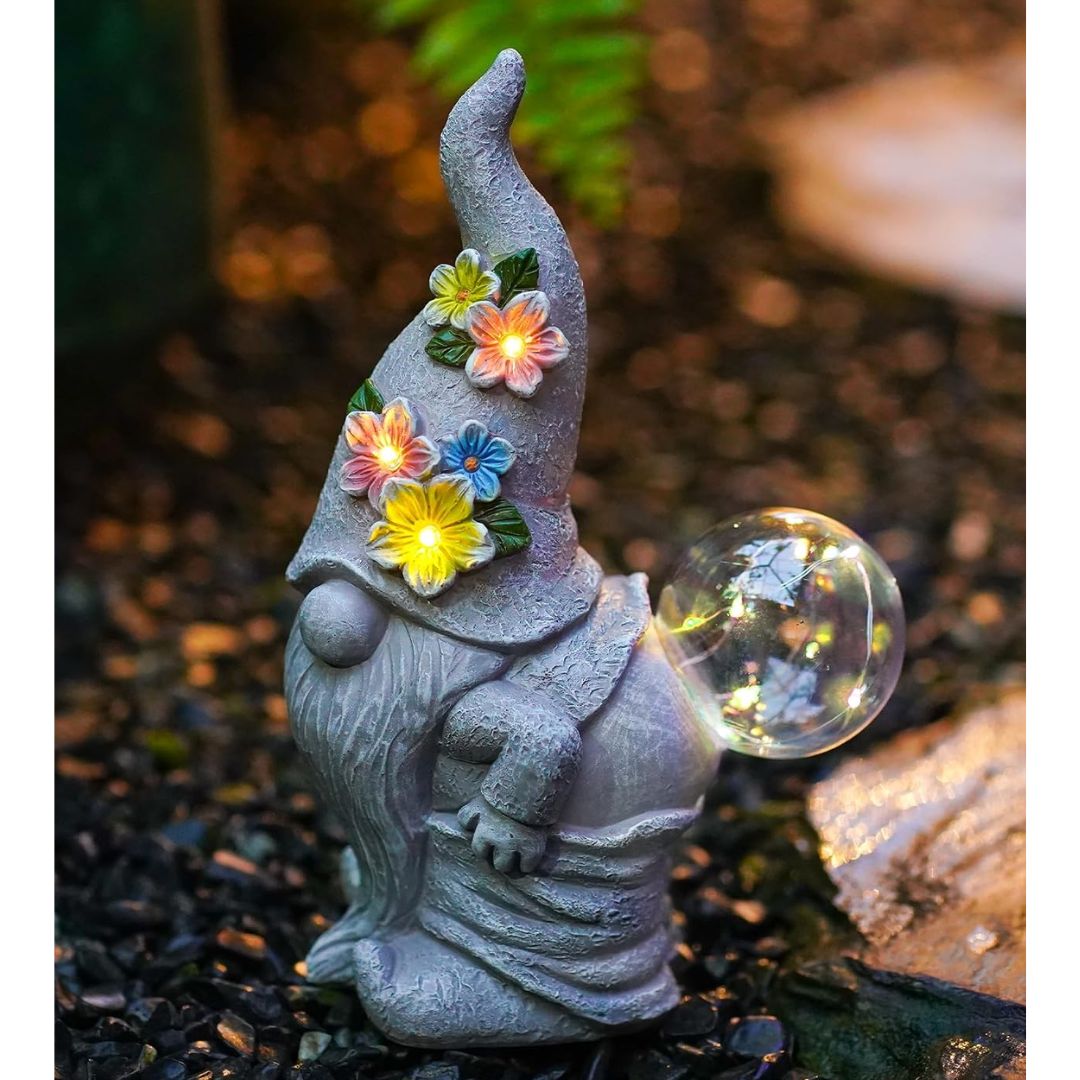 A solar garden gnome with a glowing crystal ball in a garden setting.