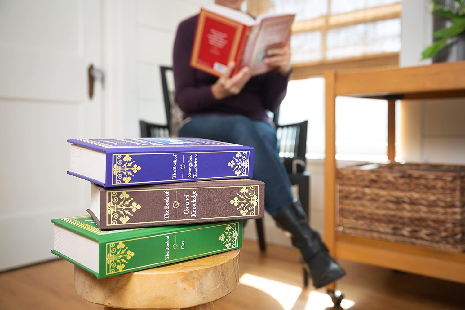 Stack of books on a small table with a person reading in the background