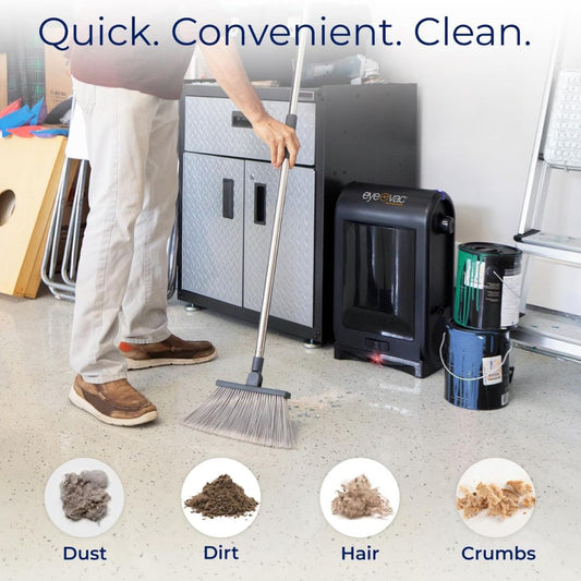 Person using a broom to clean a garage floor with cleaning products displayed with a touchless vacuum dustpan nearby.