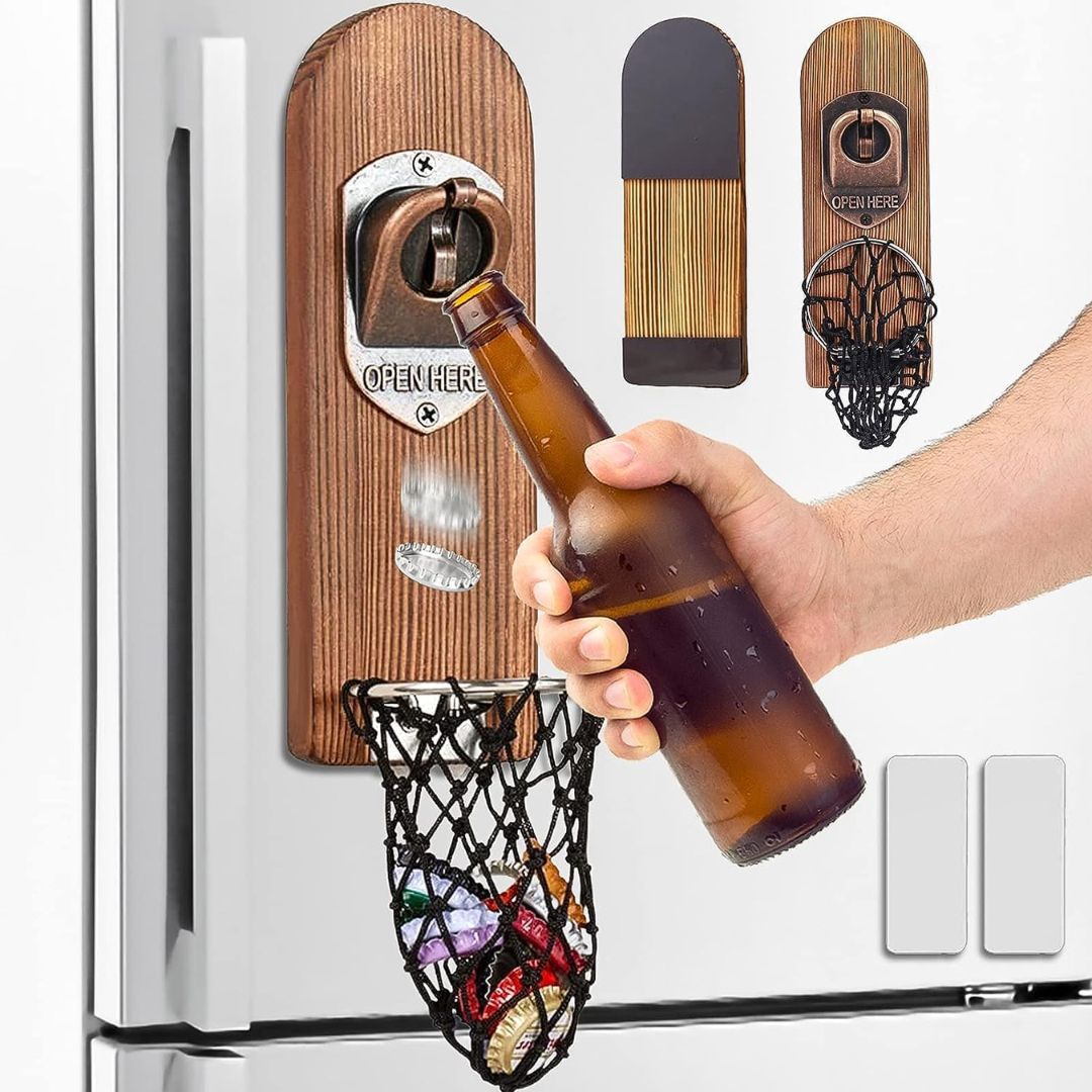 A hand opening a beer using a wooden wall mounted beer bottle cap opener with basket underneath to catch the lid.