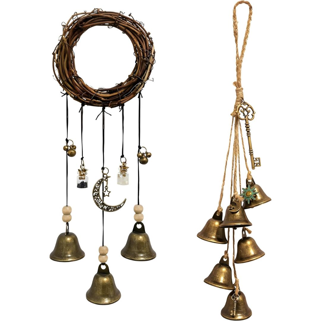 Two bohemian-style hanging witch bells wall decorations on a white background: a circular twig wreath with black cords, small bells, beads, and a crescent moon charm, and a cluster of brass bells tied with twine and an antique key.
