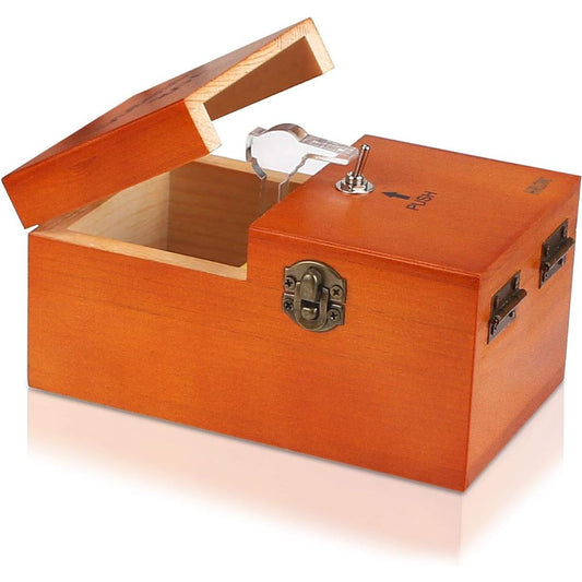 A wooden useless safe box with a warm orange-brown finish, shown open with its lid propped up. The box features a metal latch, a silver key in a clear plastic sleeve, and a small push-button lock on the top.