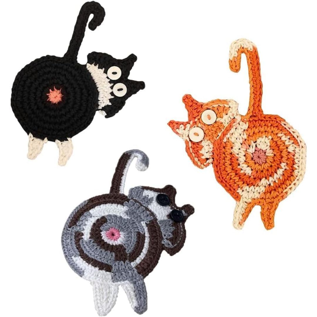 Three crocheted cat-shaped coasters in black, gray, and orange on a white background.