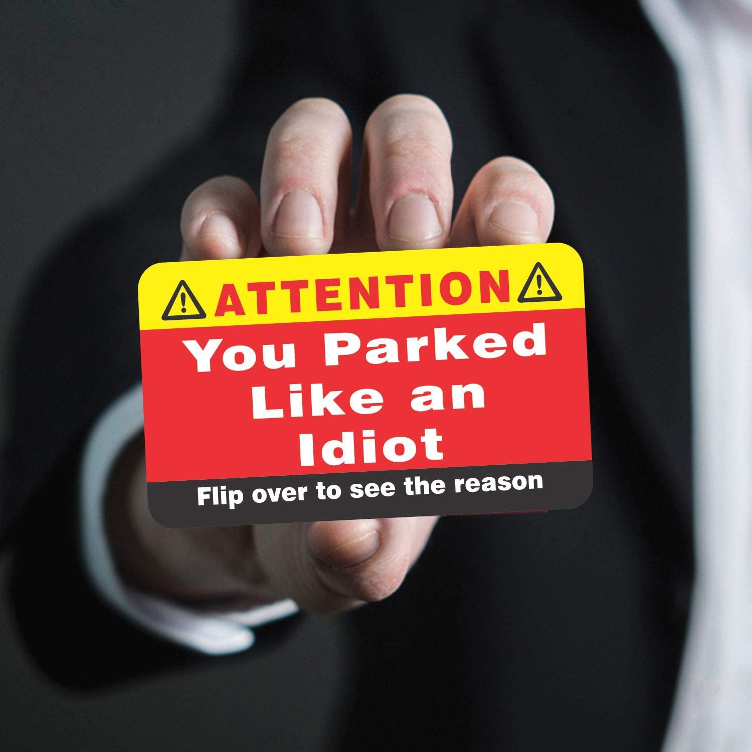 A hand is holding a business card which says, "You parked like an idiot, flip over to see the reason."