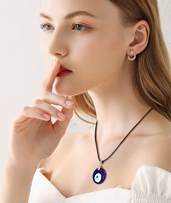 A woman is looking off to the side while wearing a necklace with a black rope and circular blue and white crystal pendant.