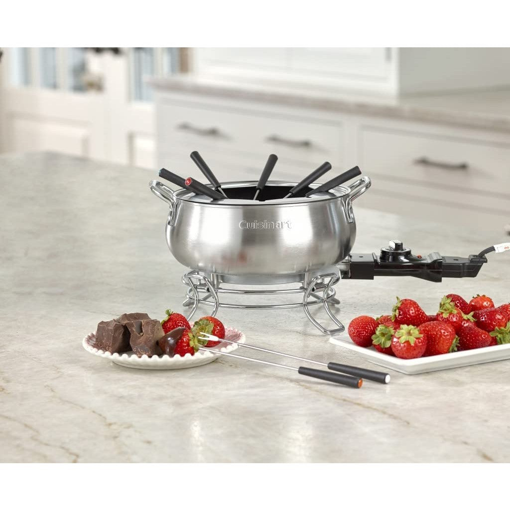 A fondue pot set is on a kitchen bench along with a tray of strawberries and pieces of chocolate.
