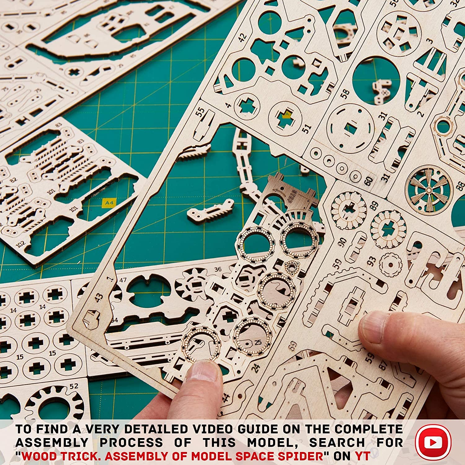 A pair of hands are removing wooden pieces from a 3D wooden spider puzzle kit.