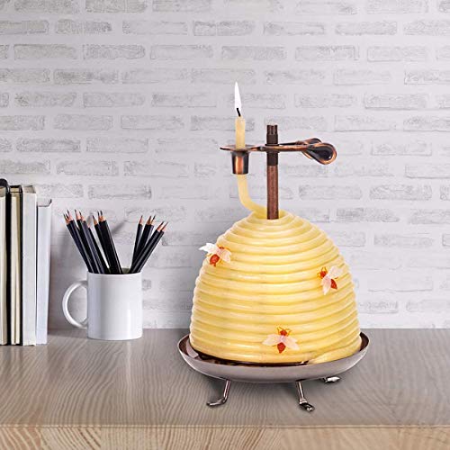 Beehive shaped beeswax candle alight on a desk