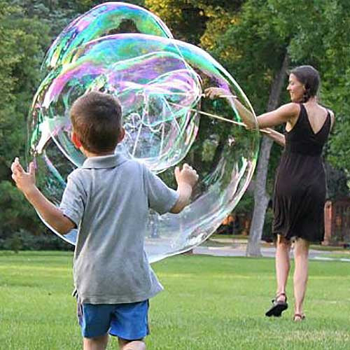 Child watching an enormous soap bubble being created outdoors