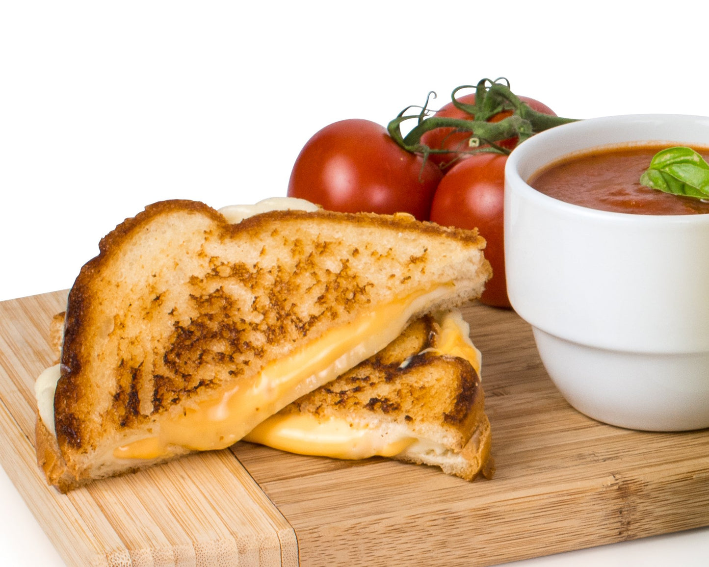 A grilled cheese toasted sandwich oozing cheese resting on a breadboard with tomatoes and tomato sauce