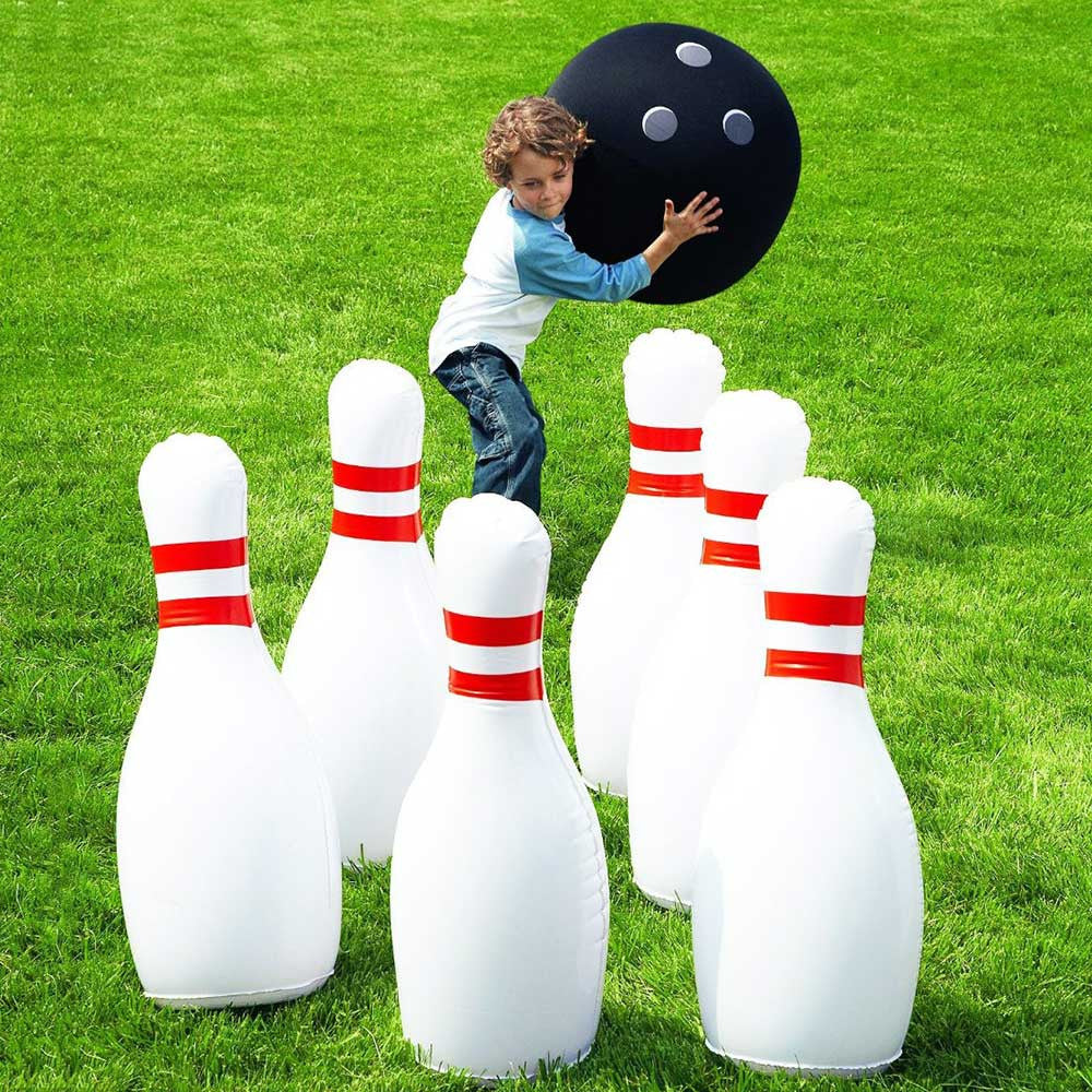 Child playing outdoor bowling with giant inflatable pins