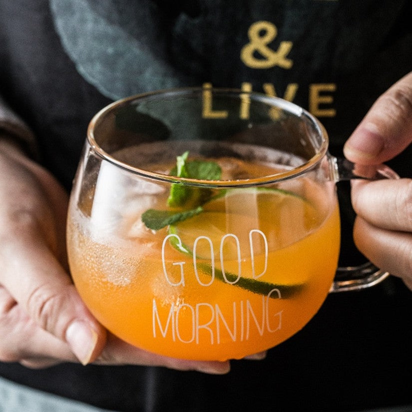 A person holding a glass good morning mug with iced tea inside