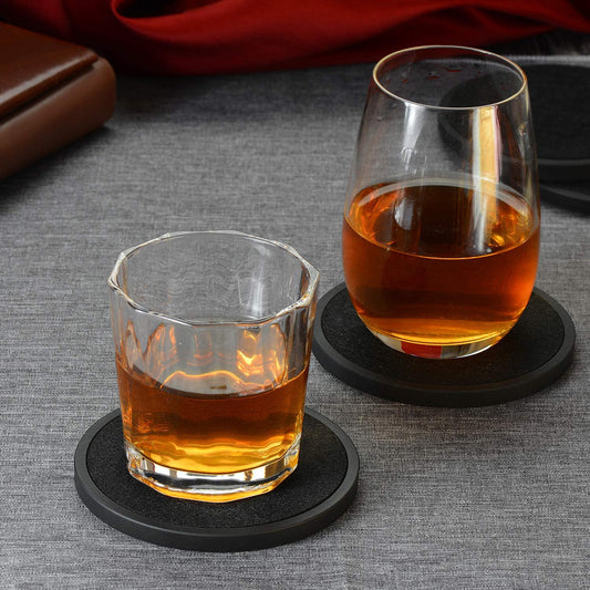 Two glasses filled with whiskey resting on two absorbent coasters.