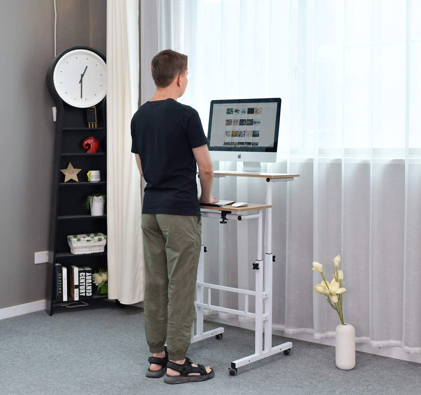 A man is standing in front of an adjustable standing desk while typing on a computer keyboard.