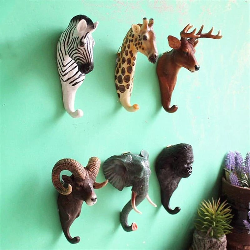 Animal shaped wall hooks on a green wall, the animal include a zebra, giraffe, deer, ram, elephant and gorilla