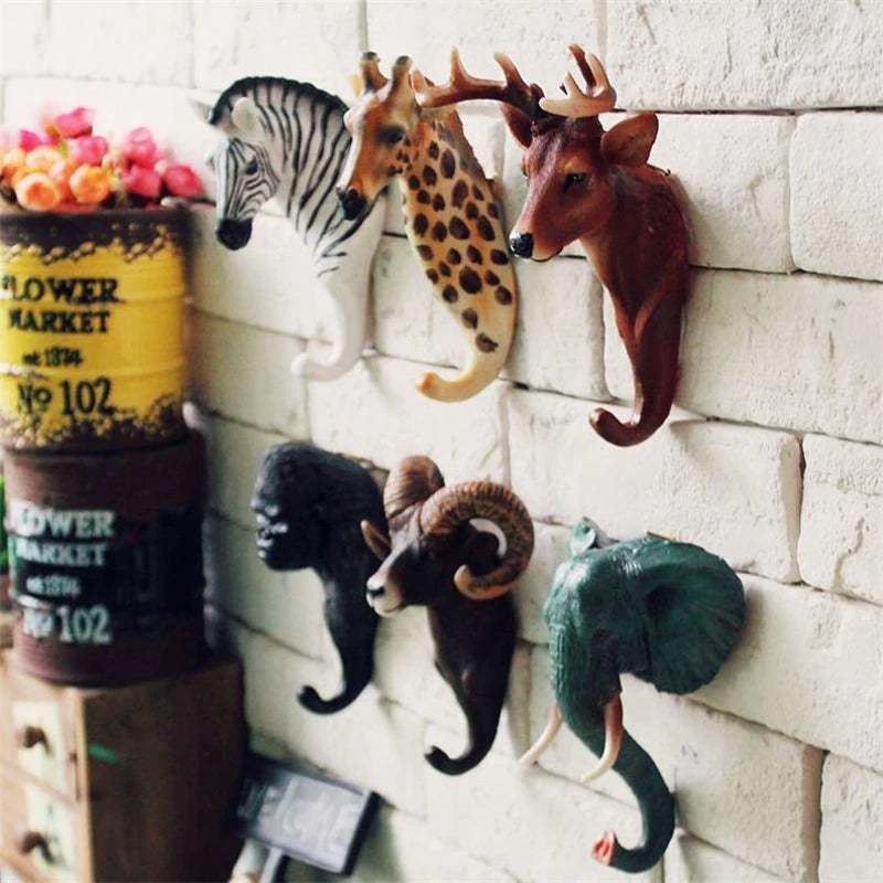 Six animal shaped wall hooks on a white brick wall. The animals include zebra, giraffe, deer, ram, elephant and gorilla,