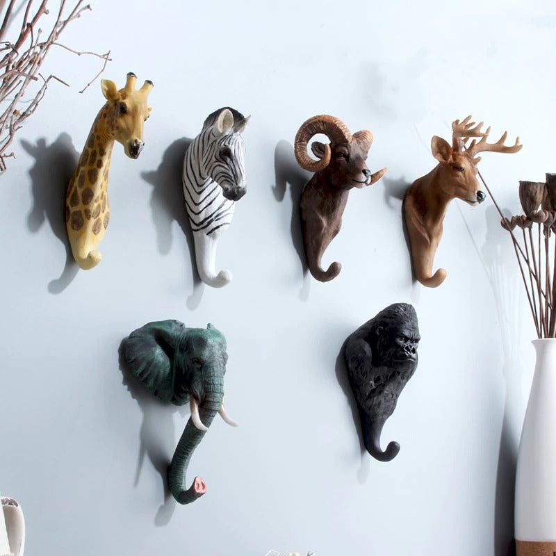 Six animal hooks on a white wall. The animals include a zebra, giraffe, deer, ram, elephant and gorilla,