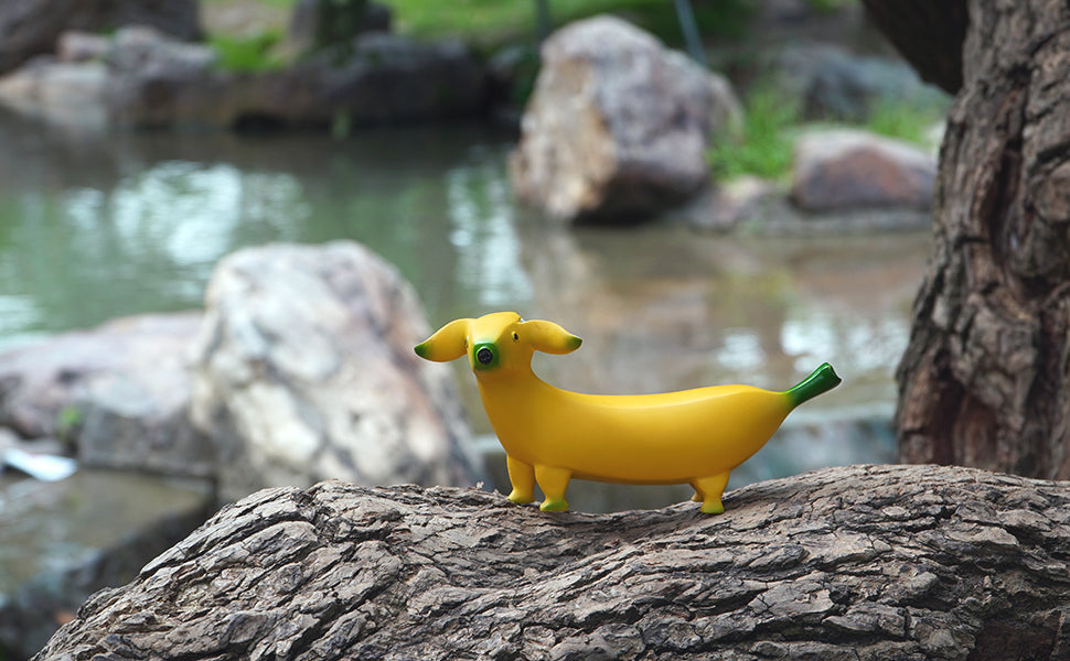 A yellow banana dog is resting on a tree truck. This is a garden ornament shaped like a banana but with a dogs head.