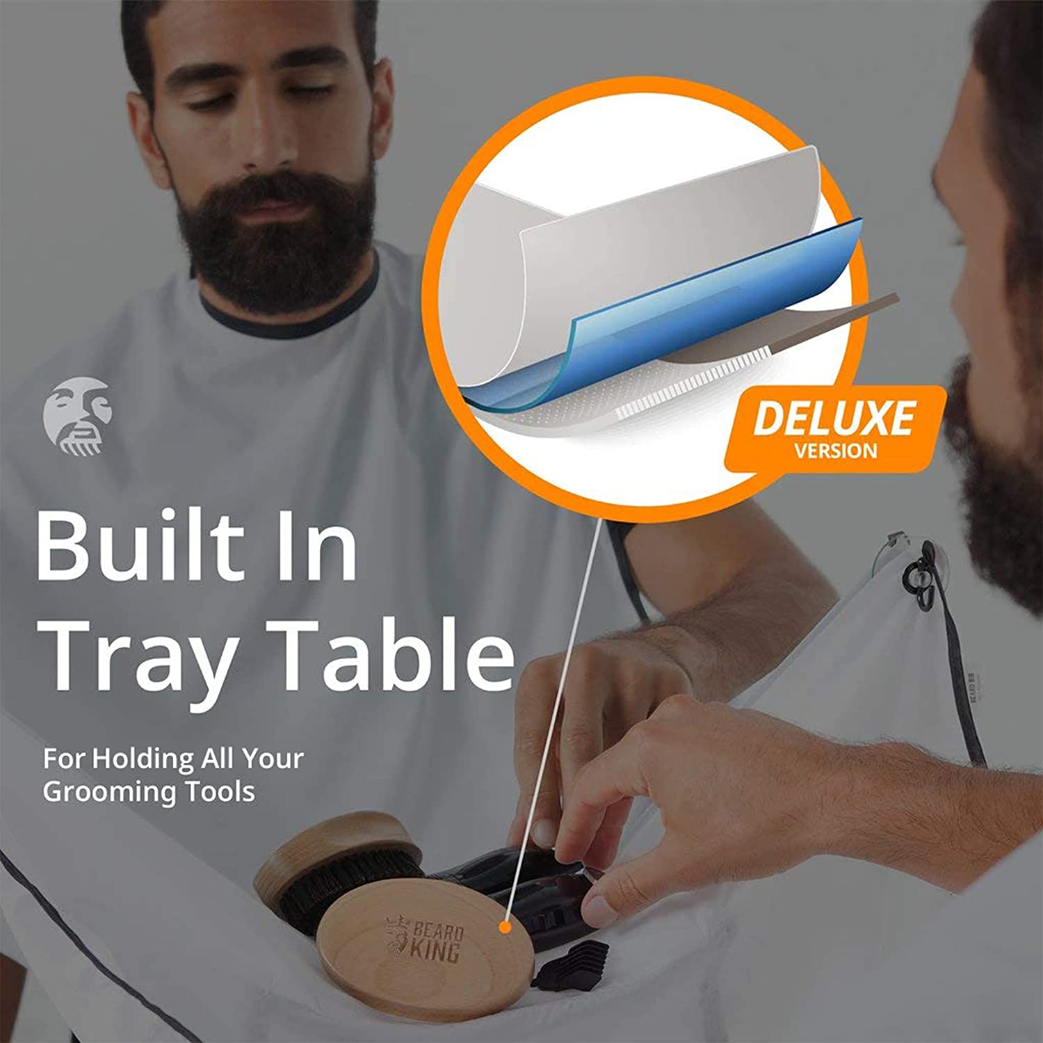 A man is placing shaving accessories into the tray for a beard bib apron. The text reads, 'Built-in tray table for holding all your grooming tools.'