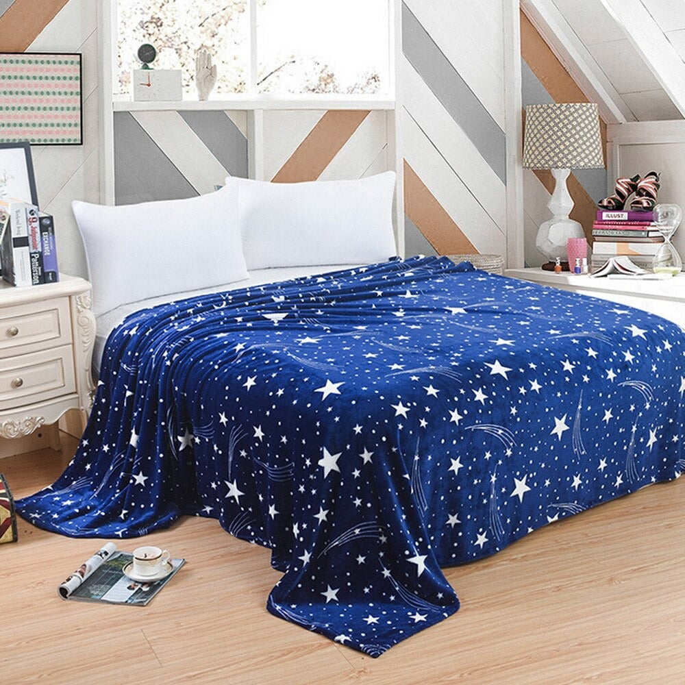 A large royal blue blanket spread out over a double bed. The blanket is covered in white stars of different sizes.