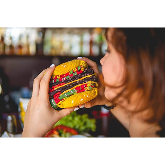 A woman is about to take a bite out of what looks like a burger but is actually pairs of socks stacked together to resemble a burger.