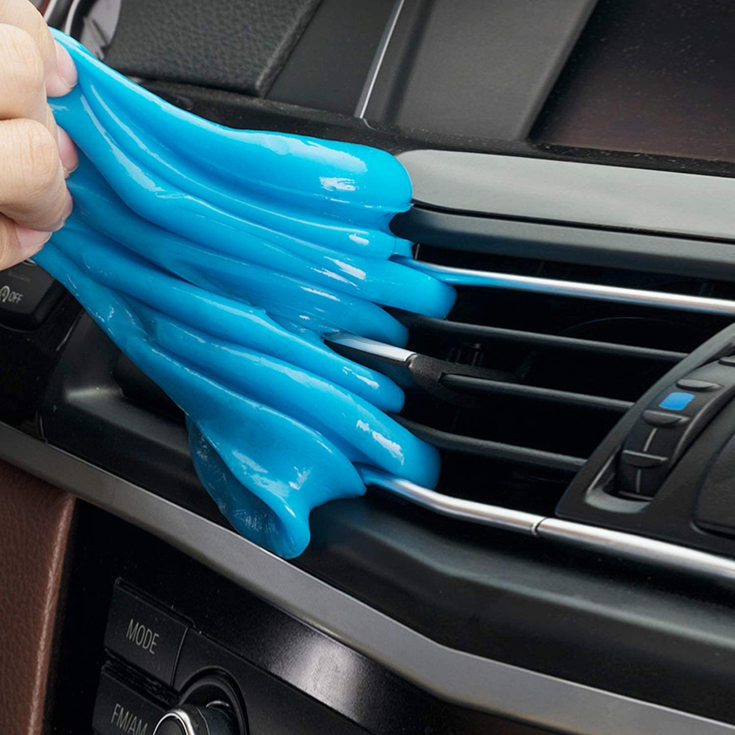 Blue colored cleaning gel being used to clean a car air vent.