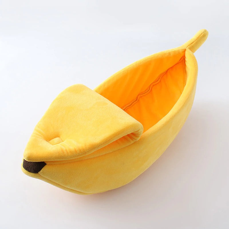 A half opened yellow banana shaped cat bed on a white background