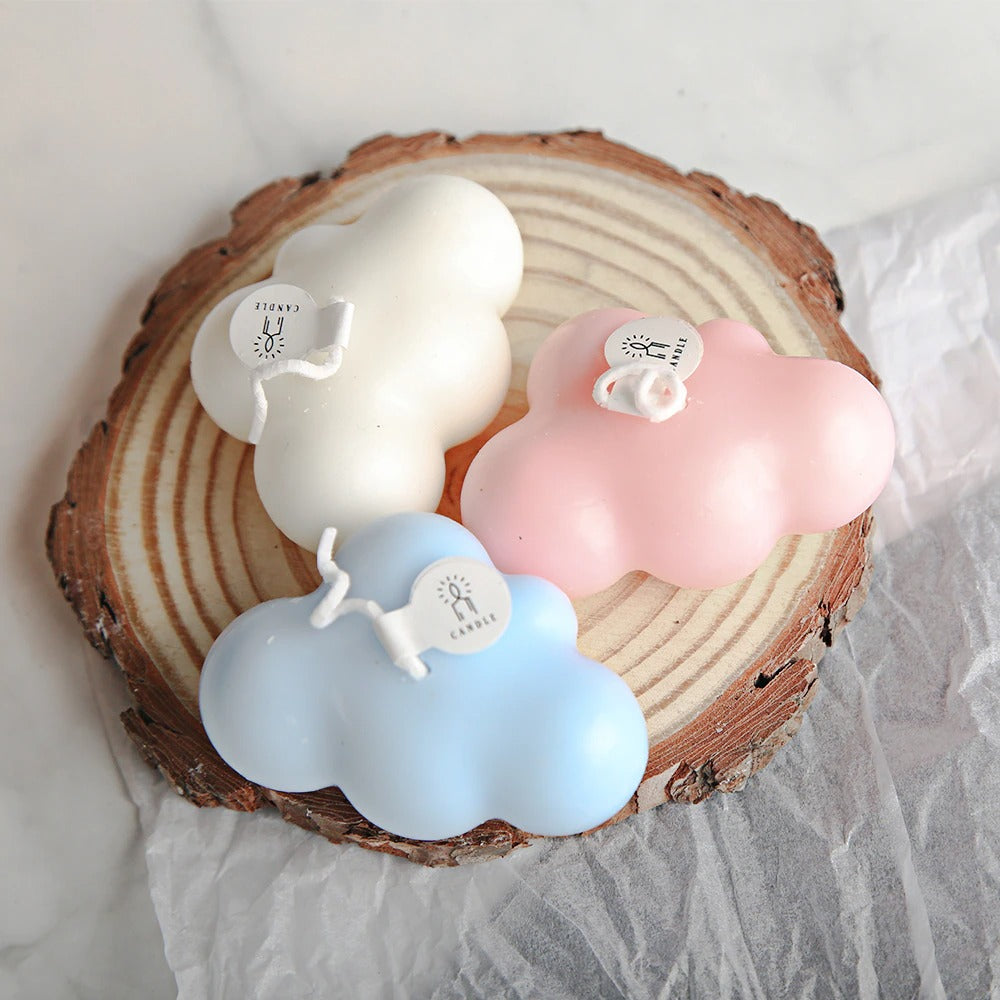 Three wax candles in the shape of clouds, the candles are white, pink and blue. These are an example of what can be made using the cloud shaped silicone molds.