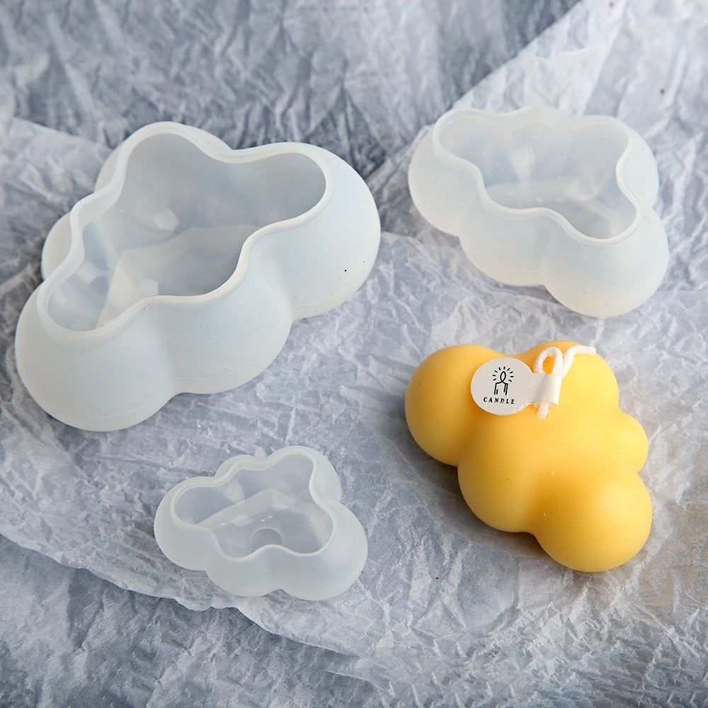 A three piece set of cloud shaped silicone molds along with a yellow cloud shaped candle made using the molds.