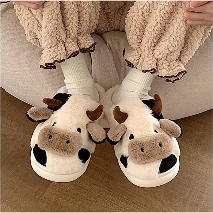 A person is wearing a pair of black and white cow slippers.
