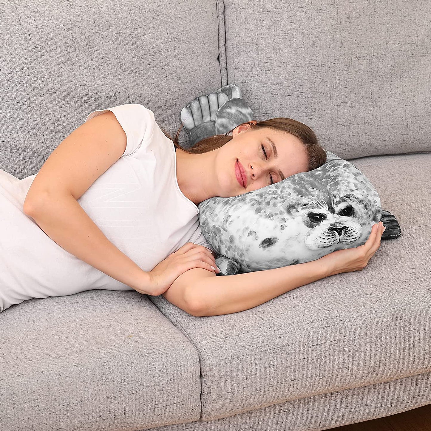 Woman asleep on a lounge with her head resting on a seal pillow
