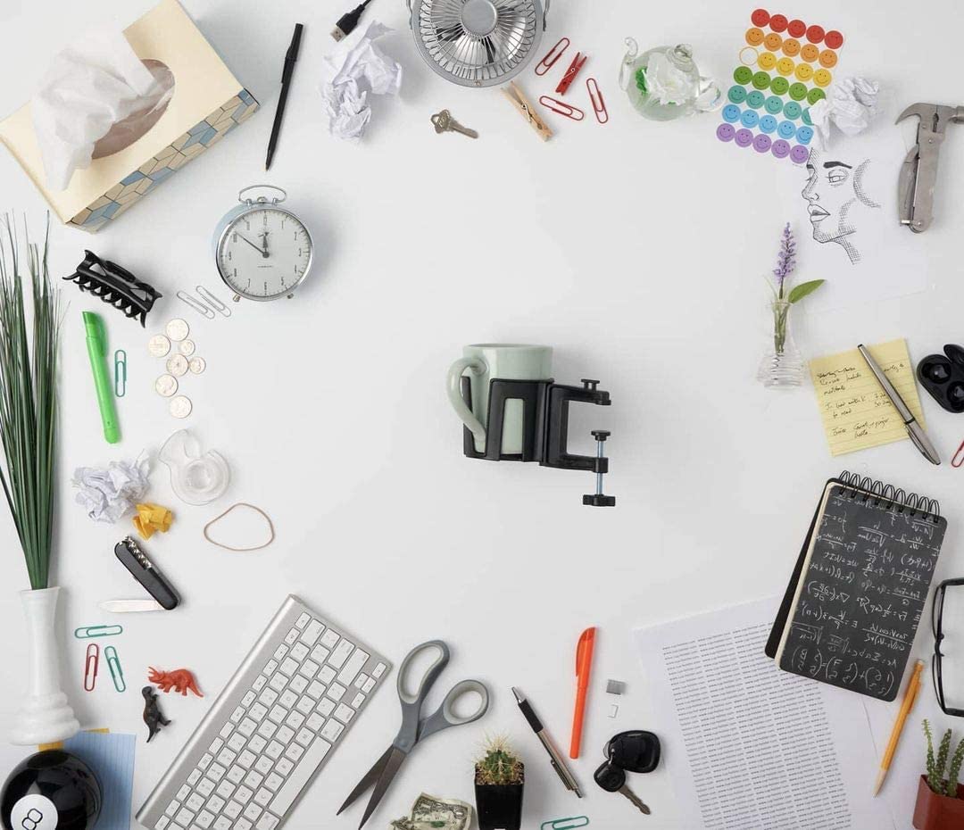 A cup holster is in the centre of a bunch of office clutter which is scattered all around it.