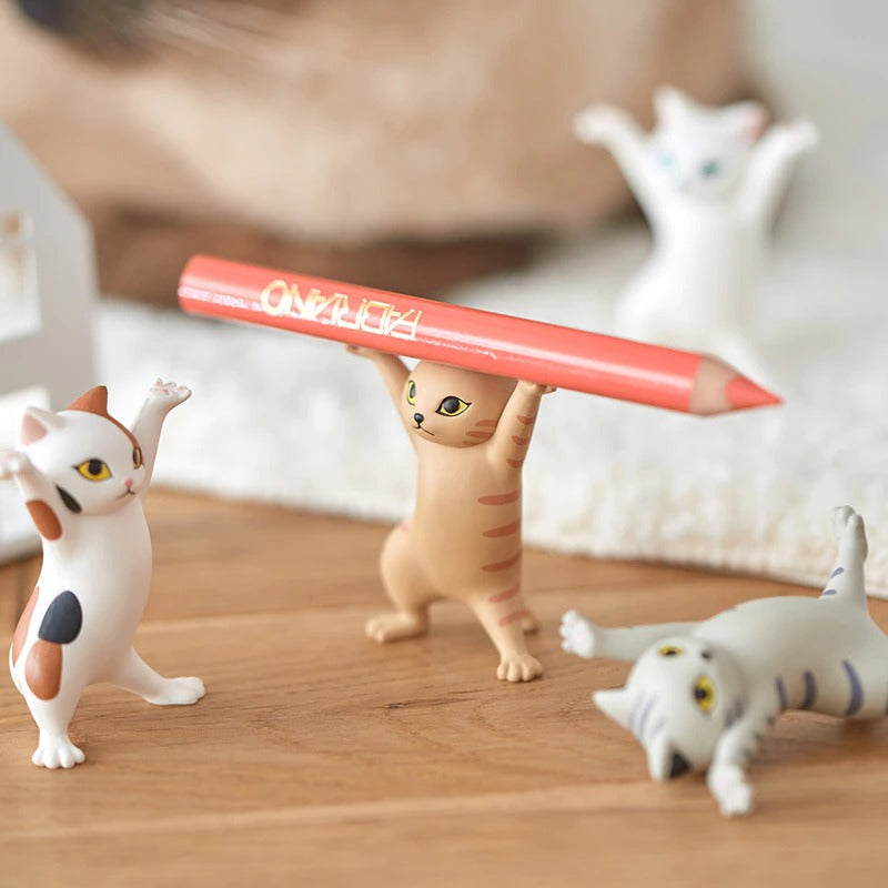 Four dancing cat figures, one is laying down, one is off to the side, one is in the background and another is holding a pencil.