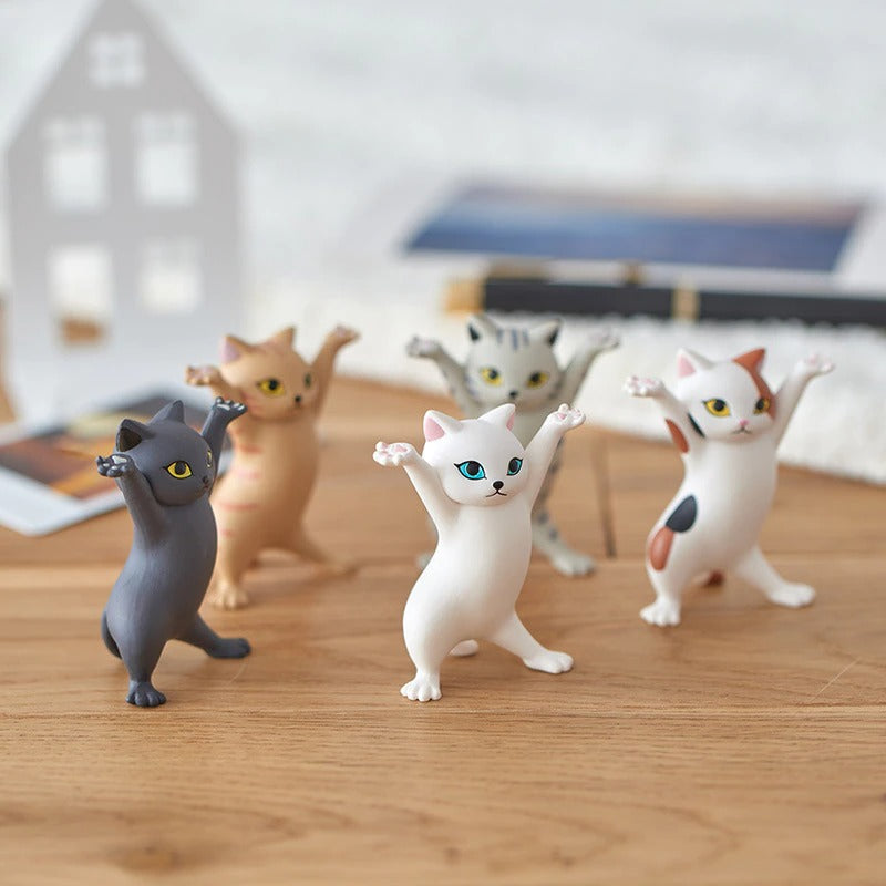Five dancing cat figures standing next to each other on a wooden table.