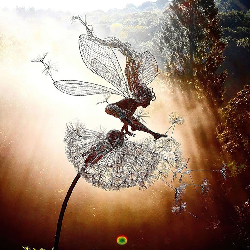 A mini metal fairy sculpture in a garden at dusk. Due to the setting sun, the outline of the sculpture looks like a little fairy is jumping over a dandelion.