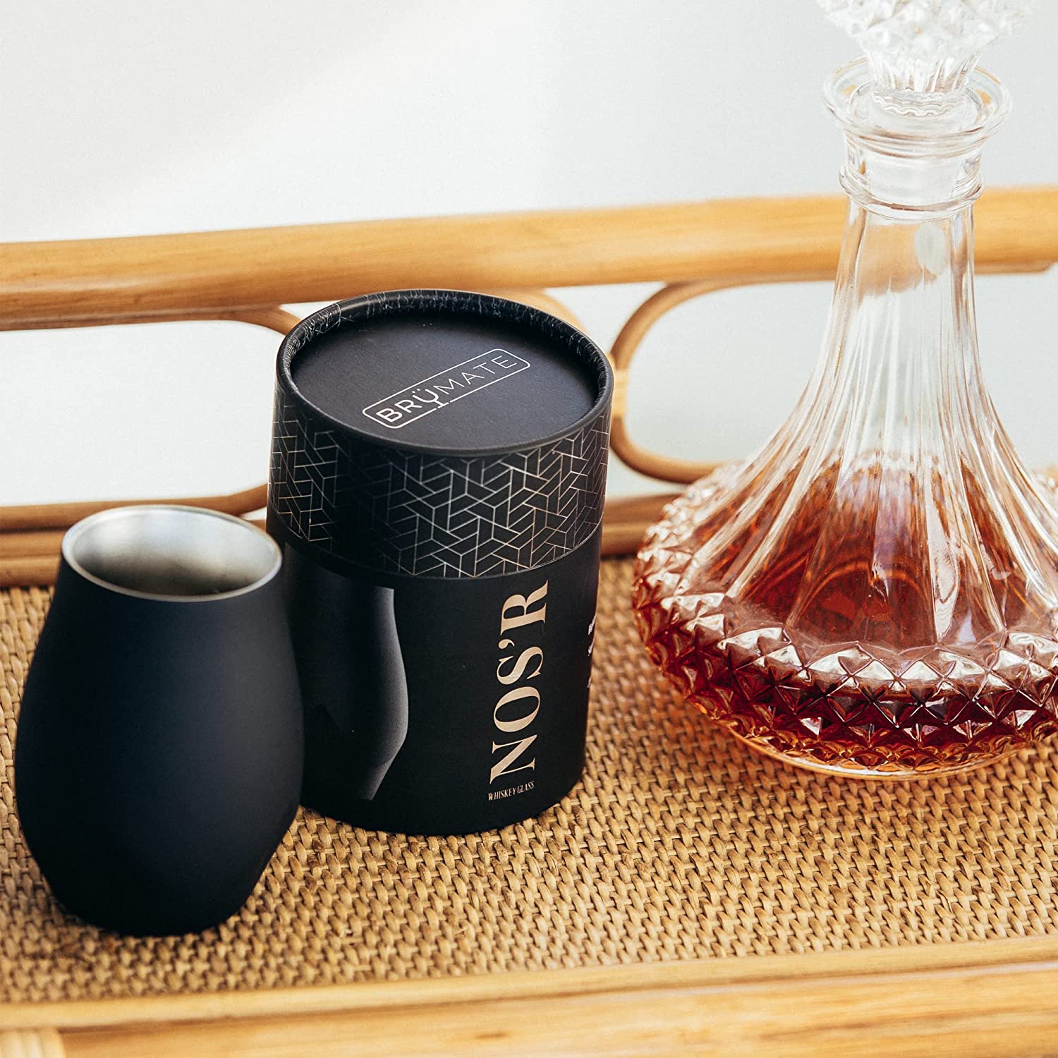 A decanter of whiskey next to a black double wall whiskey nosing glass.