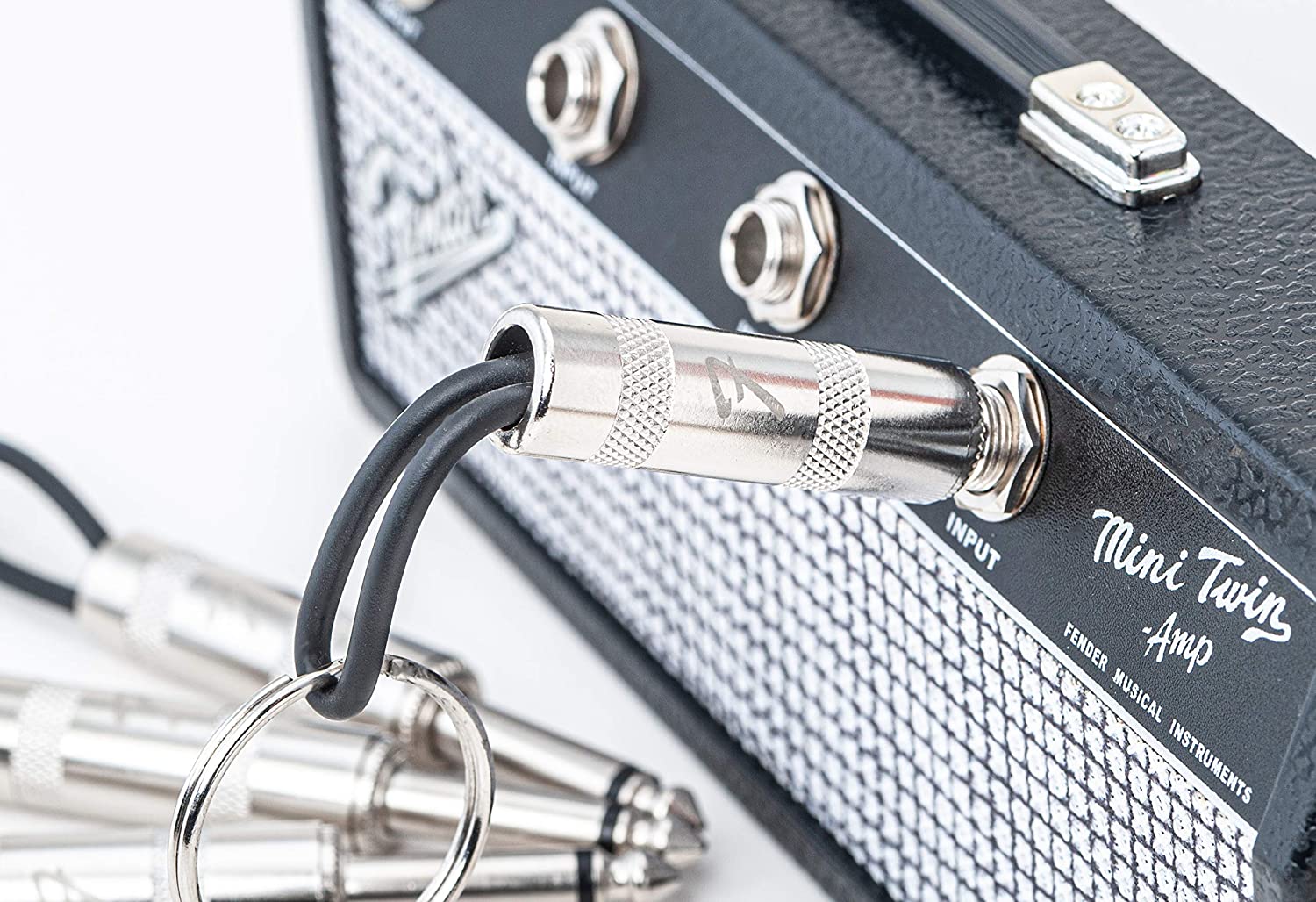 A close up view of a Fender key holder rack with one of the keychains plugged into one of the jacks.