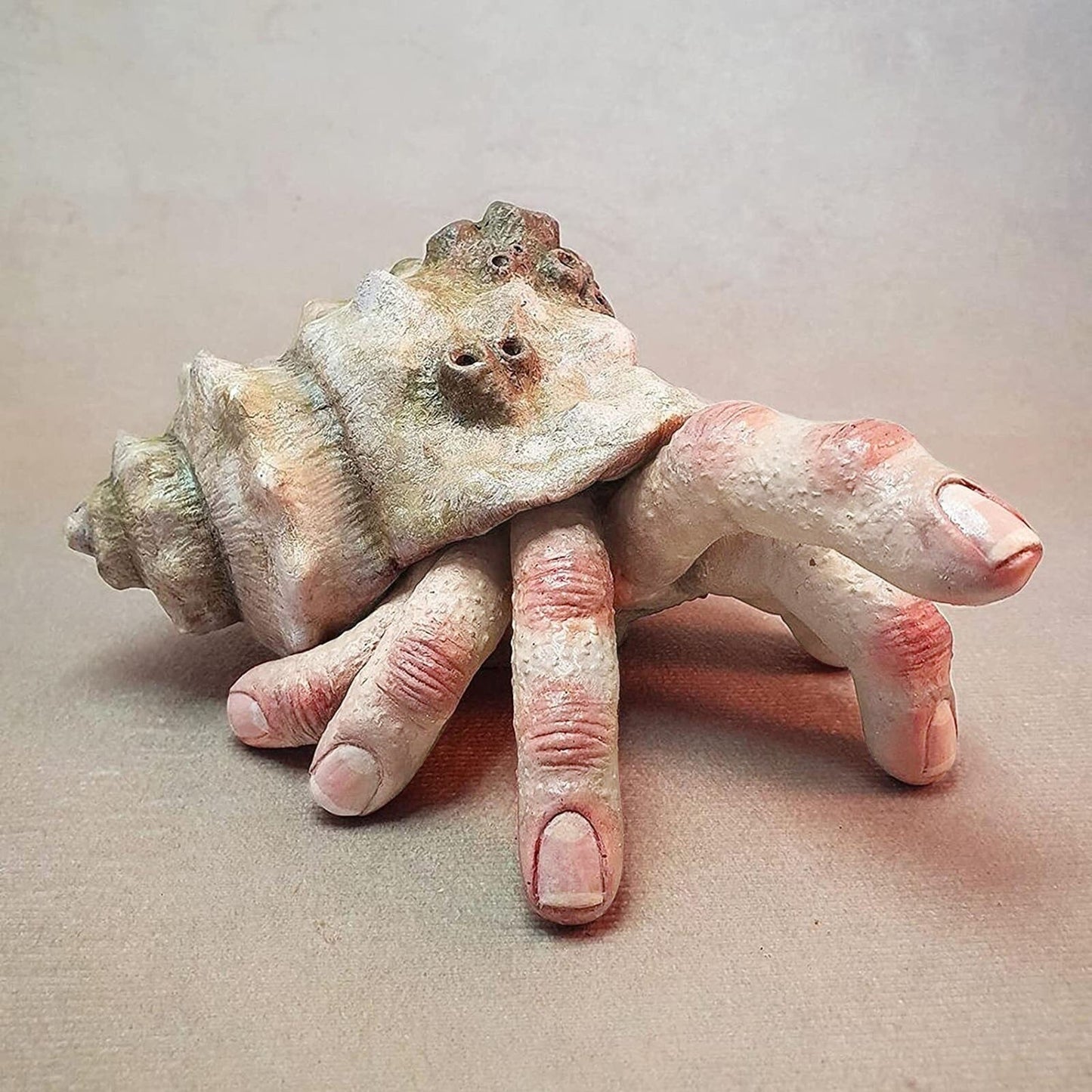 A creepy finger crab sculpture which looks like a hermit crab except human fingers are coming out of the shell instead of a crab.