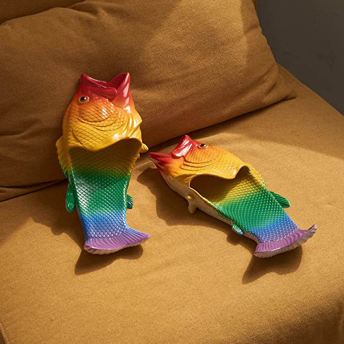 A pair of rainbow colored fish flip flops on an orange lounge.