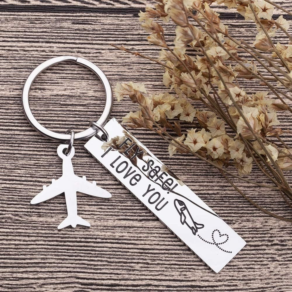 A keychain with a silver tag that reads fly safe, I love you with a silver airplane attached as well.