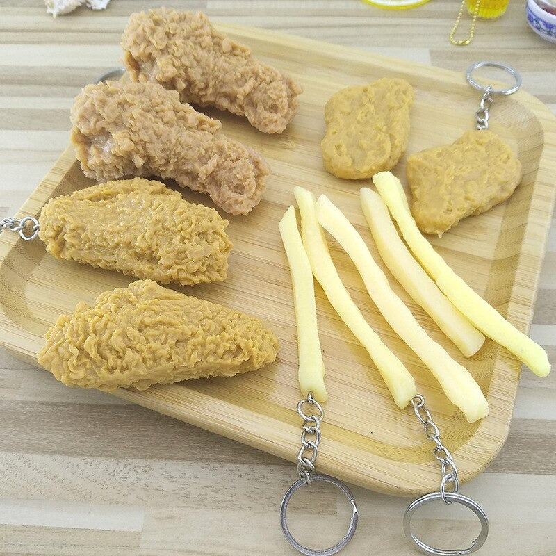 A wooden platter displaying keychains which look like chicken pieces and French fries.