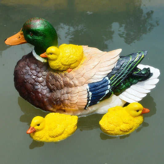 A mother duck and two yellow ducklings in a pond, these ducks are decorative garden ornaments.