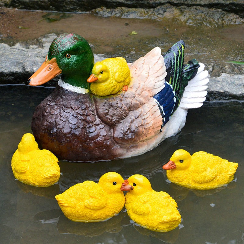 A decorative duck and ducklings made from resin used as statues. The faux ducks and ducklings are floating in a pond.